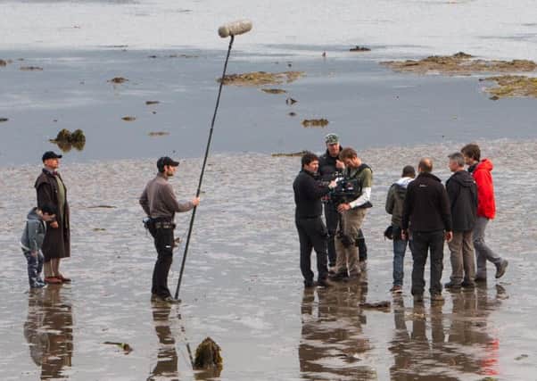 Sir Ben Kingsley (far left) pictured on the beach in Carrickfergus during filming for Robot Overlords. INCT 27-405-RM