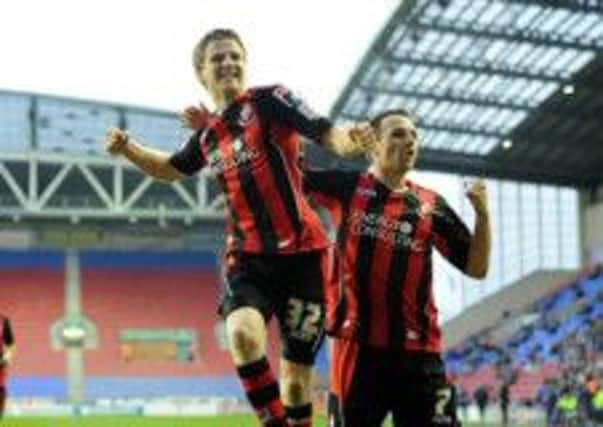 AFC Bournemouth's Eunan O'Kane (left) celebrates scoringl against Wigan Athletic with Marc Pugh