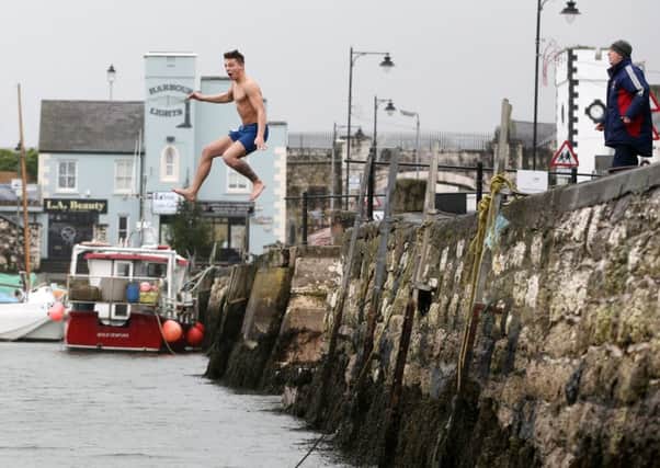 Freezin' for a reason! Late comer Stuart Gilmore makes a spectacular entrance as he jumps into the freezing water at the Spina Bifida Hydrocephalus New Year's Day charity swim at Carnlough Harbour. INBT 02-118JC