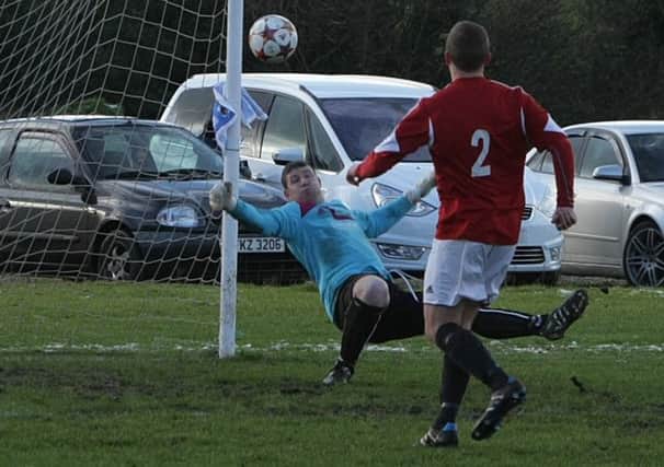 Foyle Wanderers goalkeeper Connor Thornton gets a glove to this shot and palms to safety as full back Simon Campbell watches closely, during Saturday's Irish Junior Cup clash at Bready. INLS0215MC032
