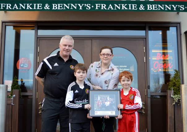 Billy O'Flaherty and players of Carniny Amateur and Youth FC present a framed club photo to Patricia Robinson of Franky and Benny's, Ballymena who are sponsors of the club's Football Development Centre.