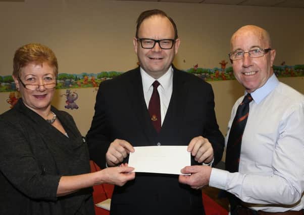 Treasure of Radio Cracker Maureen Allen and chairman Gordon Dawson present a cheque to Rev Paul Bailie of Mission Africa at the station's AGM in Montgomery's Restaurant. INBT 06-108JC