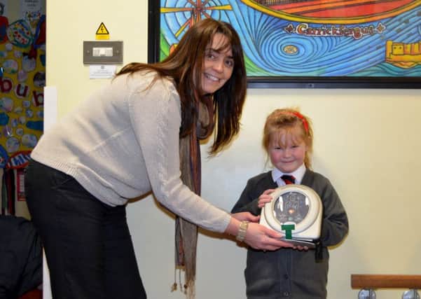 Model Primary School principal Mrs Lyons and pupil Jenny Craig, receiving a Heart Sine defibrillator donated to the school by Jenny's parents. INCT 07-124-GR