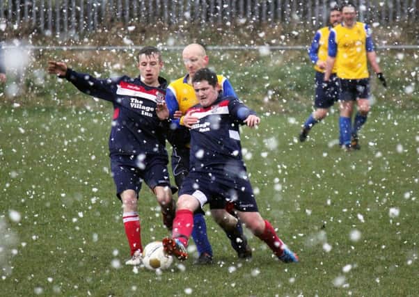 Cullybackey Olympic and Seven Towers FC players battle through the wintry conditions at Tobar Park on Saturday morning. INBT 09-964H