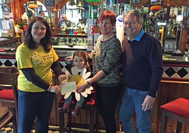 Peter and Meta Tweed (right) present a cheque for £550 to Michelle Smyth from Cancer Fund for Children that was raised by customers in Ballymenas Smithfield Arms. Also pictured is little Matilda Hendron from the town who has benefitted from the charitys range of services that includes practical and emotional support as well as free short therapeutic breaks.