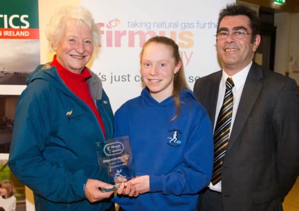 Dame Mary Peters congratulates and presents Banbridge AC member Elizabeth Little with her award for Athlete of the firmus energy Super Five series 2014 in the U13 category with Des Brown from firmus energy looking on.