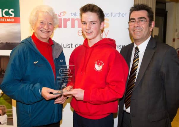 Dame Mary Peters congratulates and presents U15 City of Lisburn Athlete Bradley Mulholland with his award for Athlete of the firmus energy Super Five series 2014 with Des Brown from firmus energy looking on.