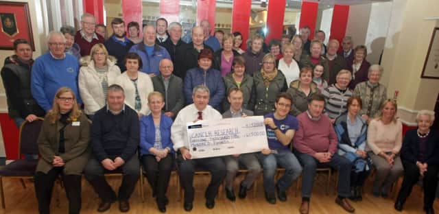 FORTY SOMETHING. Mervyn Ferris, Chairman of Ballymoney Cancer Research UK Branch, pictured at the RBL on Tuesday night presenting a cheque for the magnificant sum of £41,500.00 to Ryan McClintock, Regional Manager CR UK and Student Researcher Philip Burn. Included are committee members, volunteers and representatives from various groups who helped raise the total.INBM10-15 015SC.