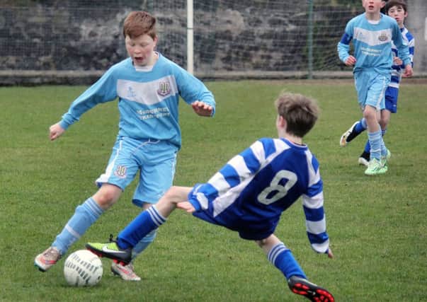 A Ballymena United player evades a sliding challenge from a Northend United under-13 opponent during Saturday's match at Smithfield. INBT 12-906H