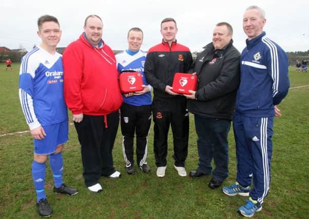Ahoghill Thistle players Alan Moore and Gary Tennant, and Ahoghill Rovers players Chris Duff and Derek Livingstone, are pictured receiving defibrillators from Gareth and David Lowry, on behalf of the Stephen Lowry Memorial Trust.  INBT11-289AC