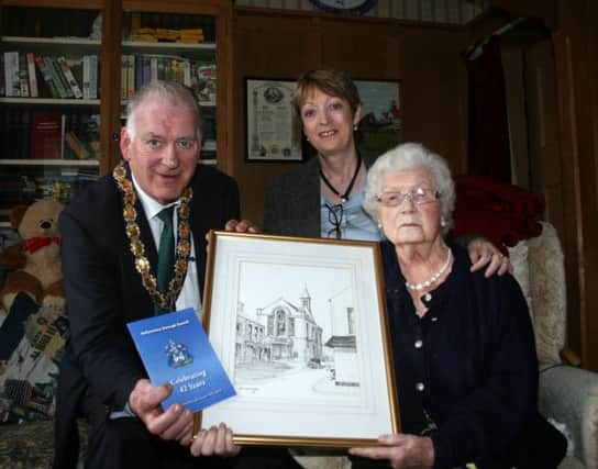 The Mayor of Ballymoney, Alderman Bill Kennedy, presents Mrs Mollie Holmes with a pencil drawing of the Town Hall by artist Jack Wilkinson as well as a booklet covering 42 years of the council. Also included is Corporate Services officer, Liz Johnston.