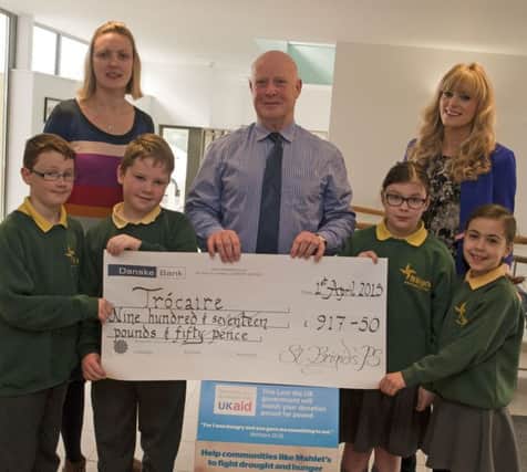 SCHOOL CHEQUE. Pupils at St Brigid's PS Reece, Conor, Annabella and Khira present a cheque for £917.50 to Ciaran O'Loan, Trocaire Volunteer on Wednesday. Looking on are staff, Roisin Hickey and Clare McAllister.INBM17-15 008SC.