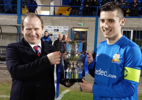 Captain Gary Donnelly receives the trophy from Colin McCullough of the Mid Ulster FA