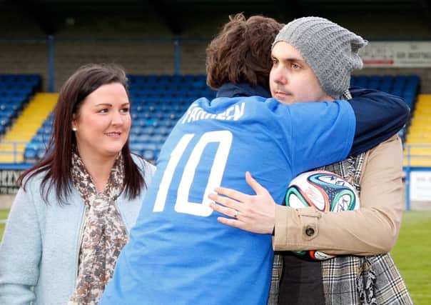 Gary Hamilton and Mark Farren embrace following the presentation of a football signed by players representing Glenavon and Derry City during last week's charity match at Mourneview Park. Looking on is Farren's wife, Terri-Louise. Pic by Alan Weir.