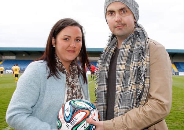 Mark Farren and his wife, Terri-Louise, with the football signed by players from the Glenavon and Derry City select sides. Pic by Alan Weir.