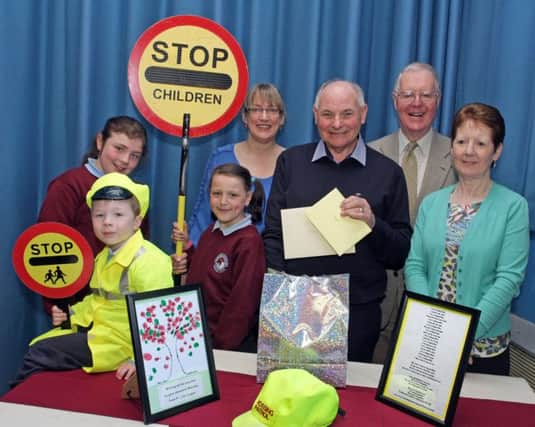 GIFTS. Malcolm Kane, who has retired from Ballycastle Integrated PS as Caretaker and Lollipop Man after 27yrs, pictured with his wife Tillie,  pupils Kate E. Katie M, Oliver, Principal Diana Evans and Dr Godfrey Brown with gifts presented to him on Friday.INBM19-15 021SC.