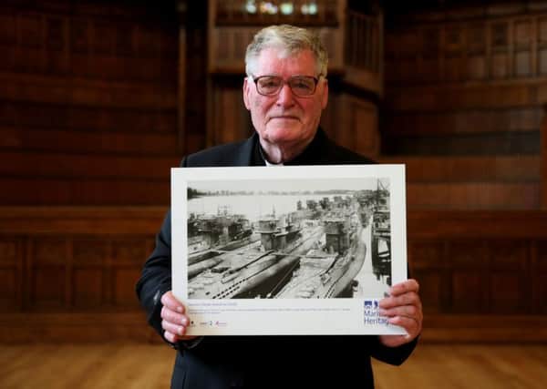 Fr Arthur O'Reilly, in the Guildhall, Londonderry, holds a photograph of German U-Boats docked at Lishally on the river Foyle in Londonderry.  : Brian Lawless/PA Wire