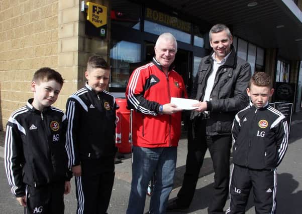 Carniny Youth U-10 players Anthony, Adam and Leon look on as Billy O'Flaherty receives a sponsorship cheque for the club's Football Development Centre from Gary Olphert, Robinson's NISA Store Manager. INBT 21-805H