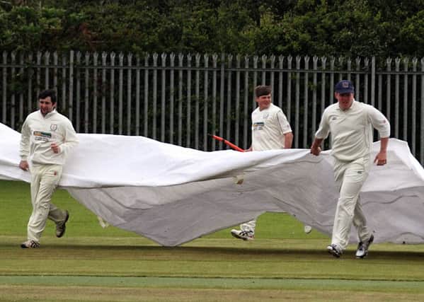 Newbuildings team members rush to cover the wicket before a shower interrupts play against Coleraine in the first round of the North West Senior Cup. INLS2115-7366MT