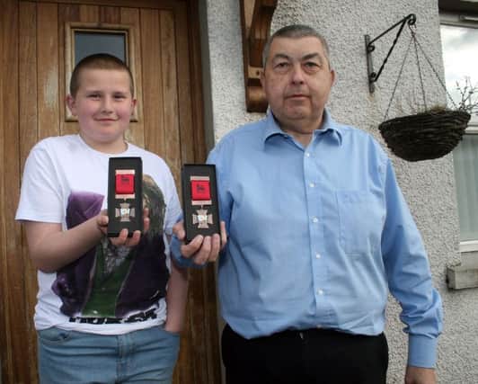 John McGregor and his son, John Junior, with the limited edition medal of Bushmills war hero Robert Quigg. The medal has gone on sale to help support a fund for the provision of a statue in Quigg's memory.. INBM24-15 S