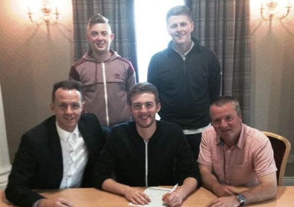 Macauley Cairns signs for Wakehurst, watched by manager Paul Muir and assistant manager Neil Candlish. Also included are the club's other new signings Lee McCaughern and Kurtis McCartney.