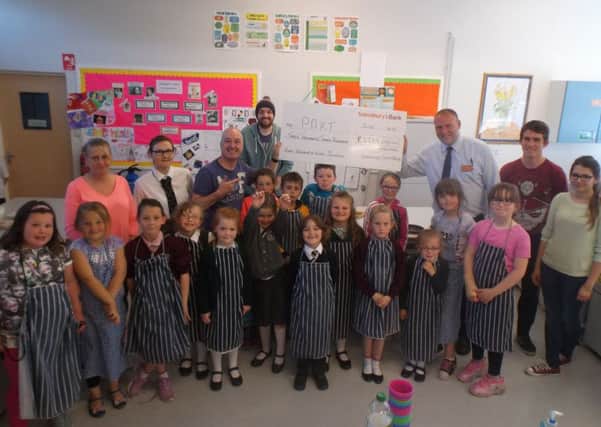 Deputy store manager David Sterrett presenting the cheque to Maurice Shearer, PAKT programme coordinator, along with parents and children from the PAKT group.  INCT 24-722-CON