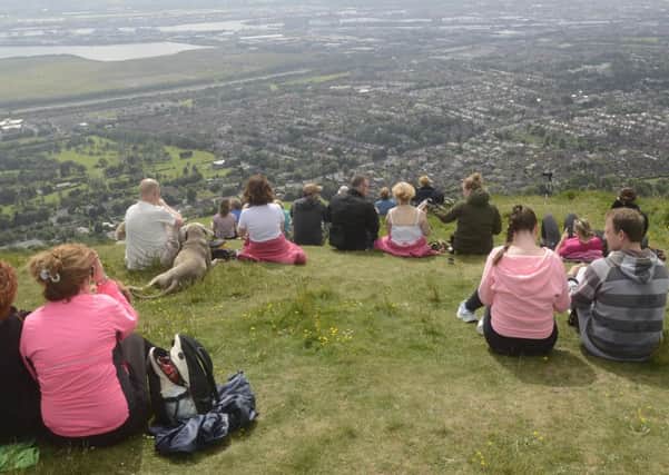 Onlookers at  Cavehill watch the  Tall Ships sail away  from the  City's dock
