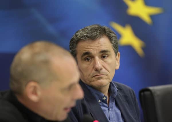 New Greek Finance Minister Euclid Tsakalotos, right, looks at outgoing Finance Minister as he speaks during a hand over ceremony in Athens, Monday, July 6, 2015. Following Sunday's referendum the Greece and its membership in Europe's joint currency faced an uncertain future Monday, with the country under pressure to restart bailout talks with creditors as soon as possible after Greeks resoundingly rejected the notion of more austerity in exchange for aid. (AP Photo/Petr David Josek)