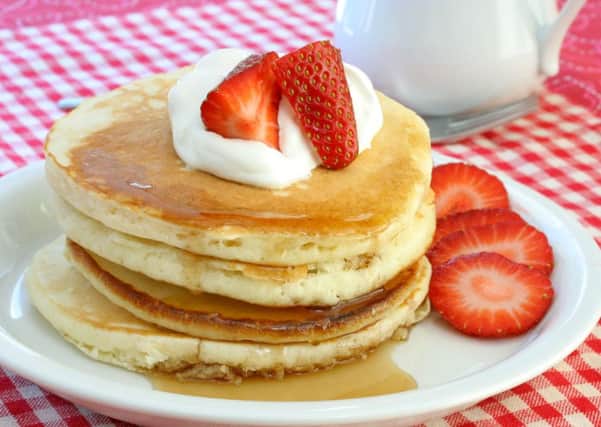 Fresh and homemade pancakes topped with cream and strawberries.