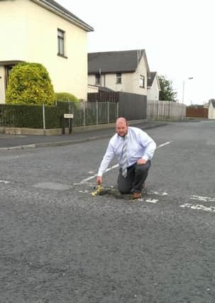 Cllr Mark Baxter draws attention to unrepaired potholes in the area.