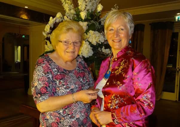 Mary Knox (left), outgoing Chairman of Ballymena Floral Art Group, hands  over the Chairman's badge to new Chairman, Ross McGookin. (Submitted Picture).