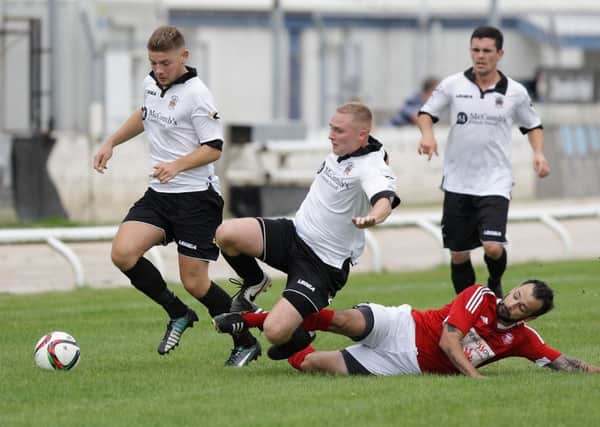 Larne's Scott Irvine slides in for a tackle against Distillery players. US1534-552cd  Picture: Cliff Donaldson
