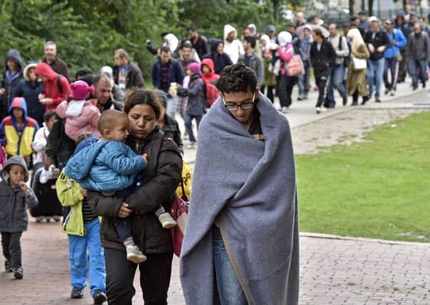 Migrants walk from the main station in Dortmund, Germany, to a hall where they get first attendance Sunday, Sept. 6, 2015. Thousands of migrants and refugees arrived in Dortmund by trains. (AP Photo/Martin Meissner)