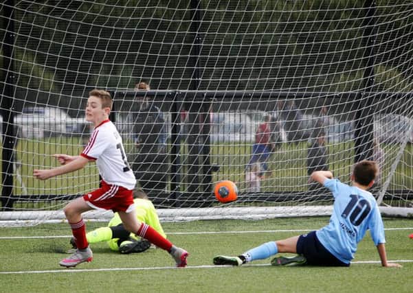 Carniny U-14 player Aiden Graffin turns a celebrates as he puts one past the Ballymena keeper. INBT37-241AC