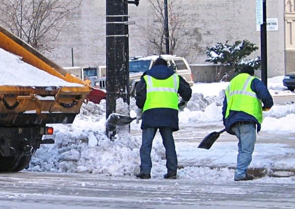 Workmen clearing snow and ice from footpaths. (Archive pic)