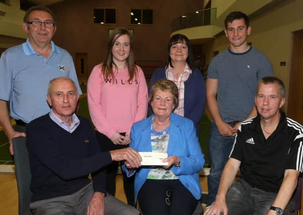 Tom Morrison presents a cheque for £350 to Betty Millar of Cancer Focus at last week's final of the Bryan Magrath Cup in 1st Ahoghill Presbyterian Church Hall. Included is event organiser Graham Wilson (front right) and back, L-R, Graham Maybin (1st Ahoghill captain) plus Bryan Magrath's widow Karen, daughter Jenifer and son Andrew. INBT 40-172CS