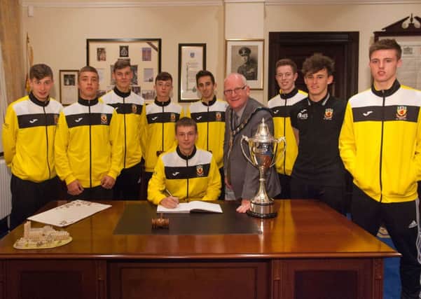 Milk Cup final goalscorer Ryan Nimick, from Whitehead, signs the council's guest book with Mayor Billy Ashe and team-mates looking on. INLT 40-902-CON