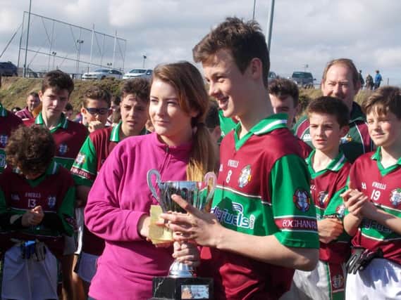 Michaela Diamond on behalf of sponsors Link It Logistics presents the cup to Eoghan Rua captain Lorcan McMullen.