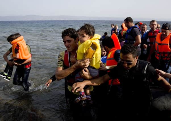 Syrian migrants arrive at the coast on a dinghy after crossing from Turkey, at the island of Lesbos, Greece. (AP Photo/Petros Giannakouris)