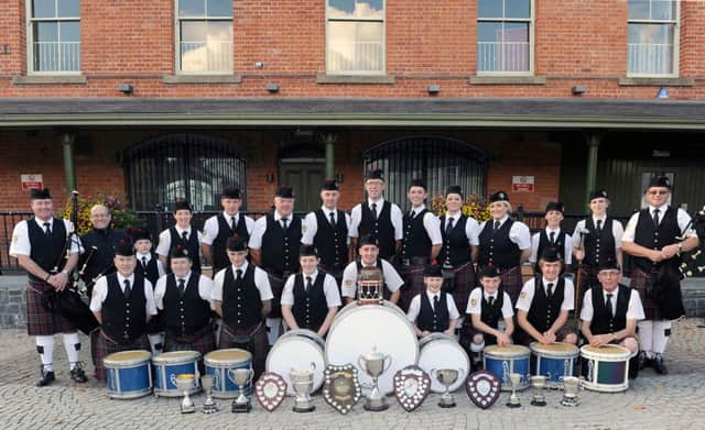McDonald Memorial Pipe Band pictured in their home town of Dromore in October 2014 with the bands winning silverware.  Included are Norman McDonald jnr, Pipe Major and Norman McDonald snr, Founder & President (left) and Vikki Singer, Drum Major and Ronnie McDonald, Pipe Sergeant (right) and Trevor Clydesdale, Drum Sergeant (left in front row).