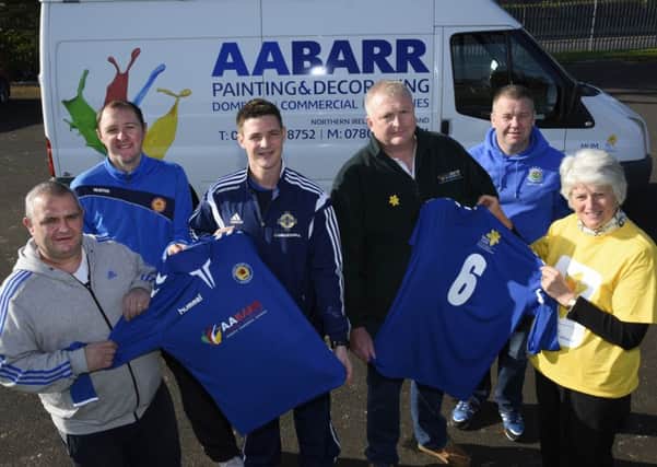 Alwyn Barr, third from right, of AA Barr Painting & Decorating, handing over a sponsored soccer strip to Lincoln Courts Football Club, represented by, from left, Darren Burnett, Gary McClements, Kolyn Patterson, manager, and Gary Dunn, in tribute to his mother, who passed away this week last year after battling with cancer. Included is Joan Doherty, of the City Friends of Marie Curie, whose logo has been printed on the shirts in appreciation of the work of Marie Curie nurses in their care of his mother. INLS415-136KM