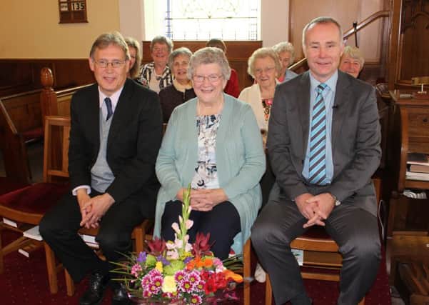 L-R: Assistant Minister at Raloo Presbyterian Church Chris Barron, Nance Wallace with her flowers and Minister Neil Bingham. Members of the Church Choir are seated behind.. INLT-44-707-con