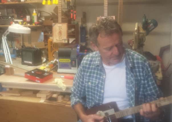 Brian Anderson playing one of the cigar box guitars he crafted. INNT 45-813CON