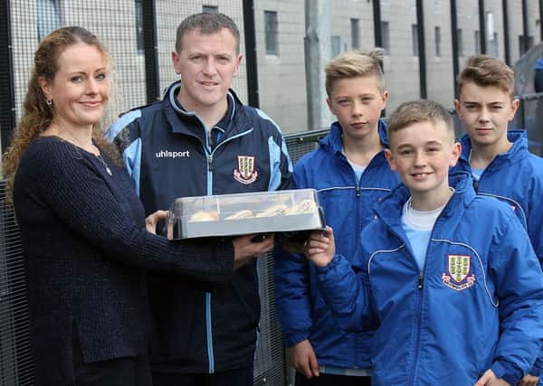 Jennifer Herald, of Subway Ballymena, presents a platter of food to Ballymena United U-14s manager Colin Lorimer watched by some of the hungry lads at Saturday's match against Portadown. INBT 45-810H
