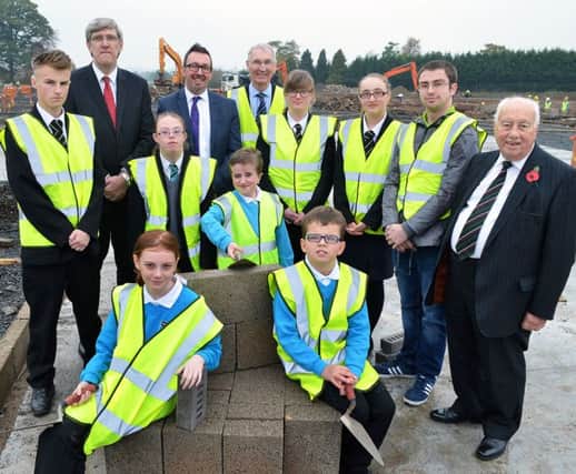 Raymond Feeters, Castle Tower principal, with school pupils, Education Minister John O'Dowd, Rev. Robert Coulter, Chairman Board of Governors, and Gerry Gray, Felix O Hare & Co Lltd, get ready to lay some blocks at the new school site. INBT 46-803H