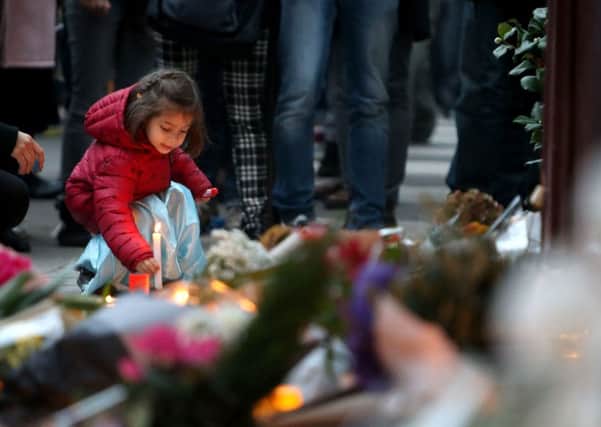 A young girl leaves a lit candle outside Le Carillon bar, Paris, one of the venues targeted in the attacks.