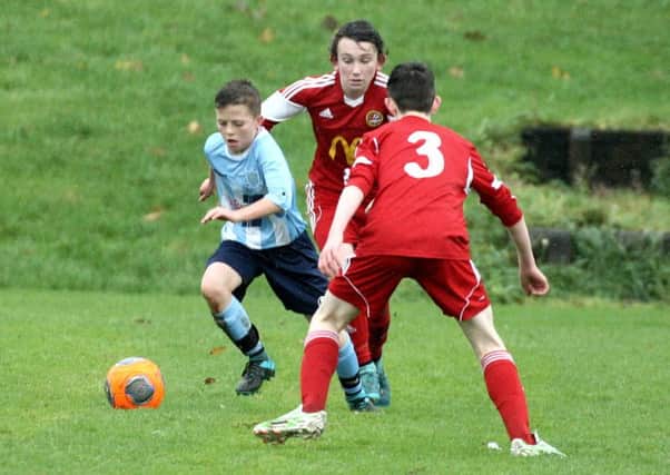 A Ballymena United under-14 player nips past two Carniny Youth opponents.