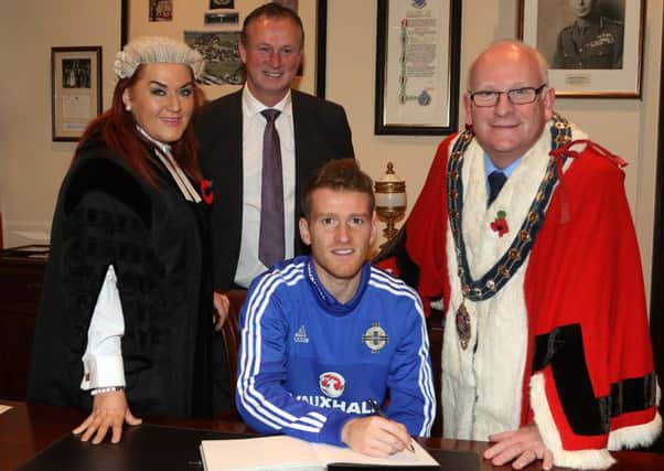 Steven Davis signs the visitors' book at last week's civic reception while Northern Ireland manager Michael O'Neill looks on. Included is Mid & East Antrim chief executive Anne Donaghy and Mayor of Mid & East Antrim Cllr Billy Ashe. INBT 47-170CS