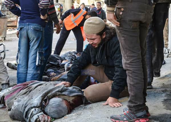 In this photo provided by the Syrian anti-government activist group Ariha Today, which has been authenticated based on its contents and other AP reporting, a Syrian man weeps near the body of a victim who was killed by airstrikes believed to be carried out by Russian warplanes in the center of Ariha town in the northwestern province of Idlib, Syria, Sunday, Nov. 29, 2015. Syrian opposition media is reporting that airstrikes believed to be carried out by Russian warplanes have killed and wounded dozens of people in a northwestern Syrian market. (Ariha Today via AP)