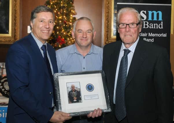 Paul Girvan MLA (left) and John Fittis (centre) present a gift to Major Sinclair Memorial chariman Cartie McAllister in recognition of the band being crowned 2015 Grade 4A World Champions. INNT 50-523CON